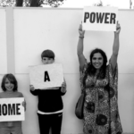 People holding up signs saying "Every Home a Power Station"