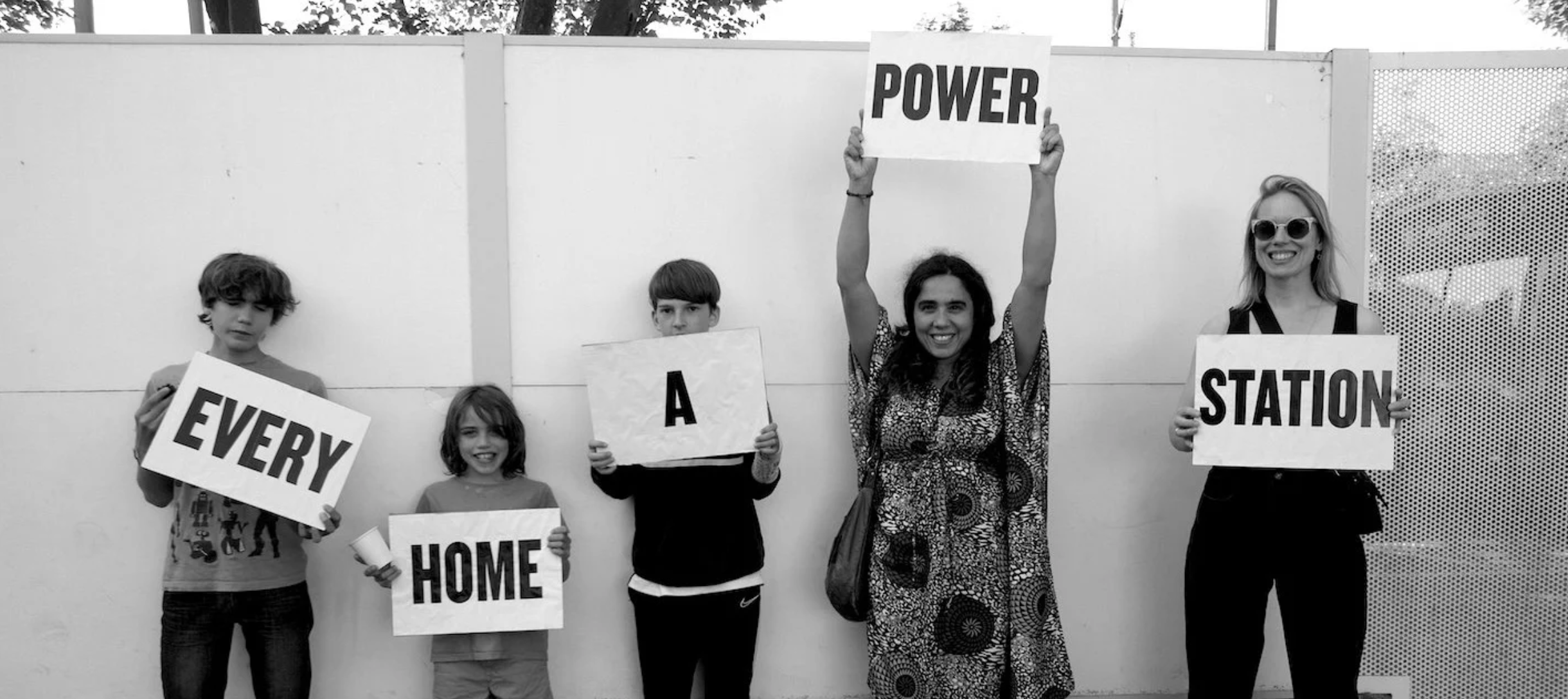 People holding up signs saying "Every Home a Power Station"